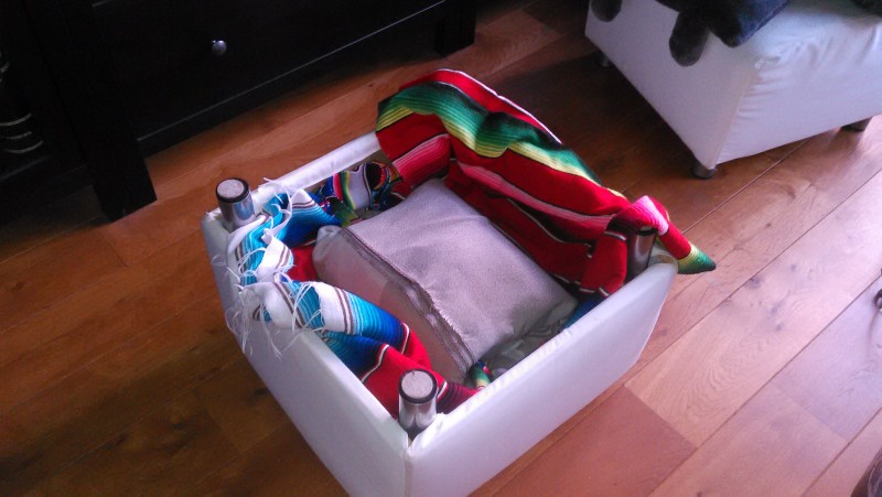 ottoman upside down with two blankets, one folded over hot pot